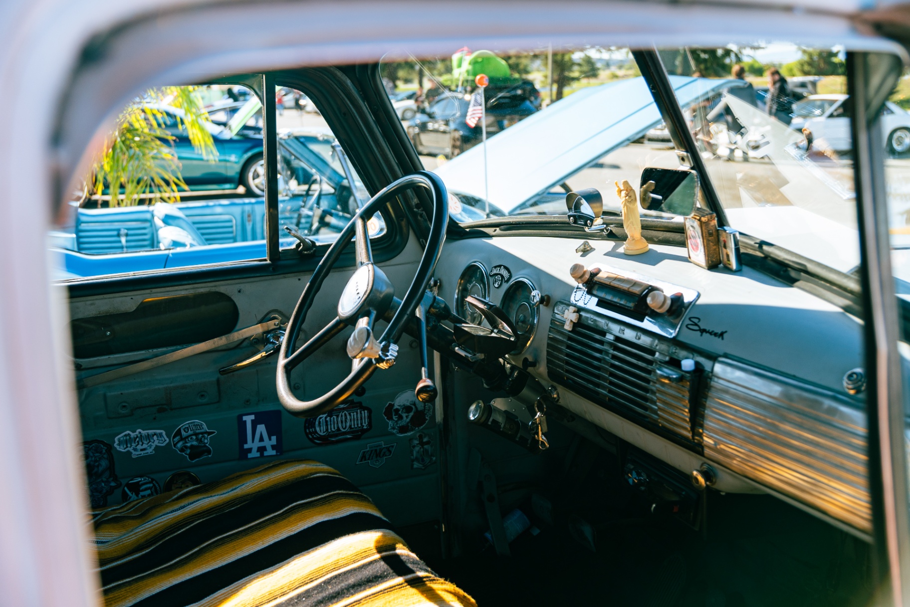 Interior of a stickered classic Chevy pickup with serape bench seat