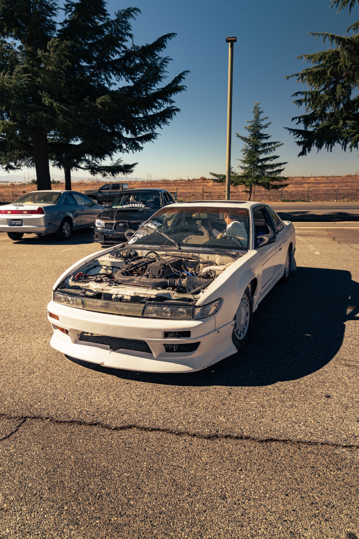 White Nissan Silvia S13 with hood up parked at the meet