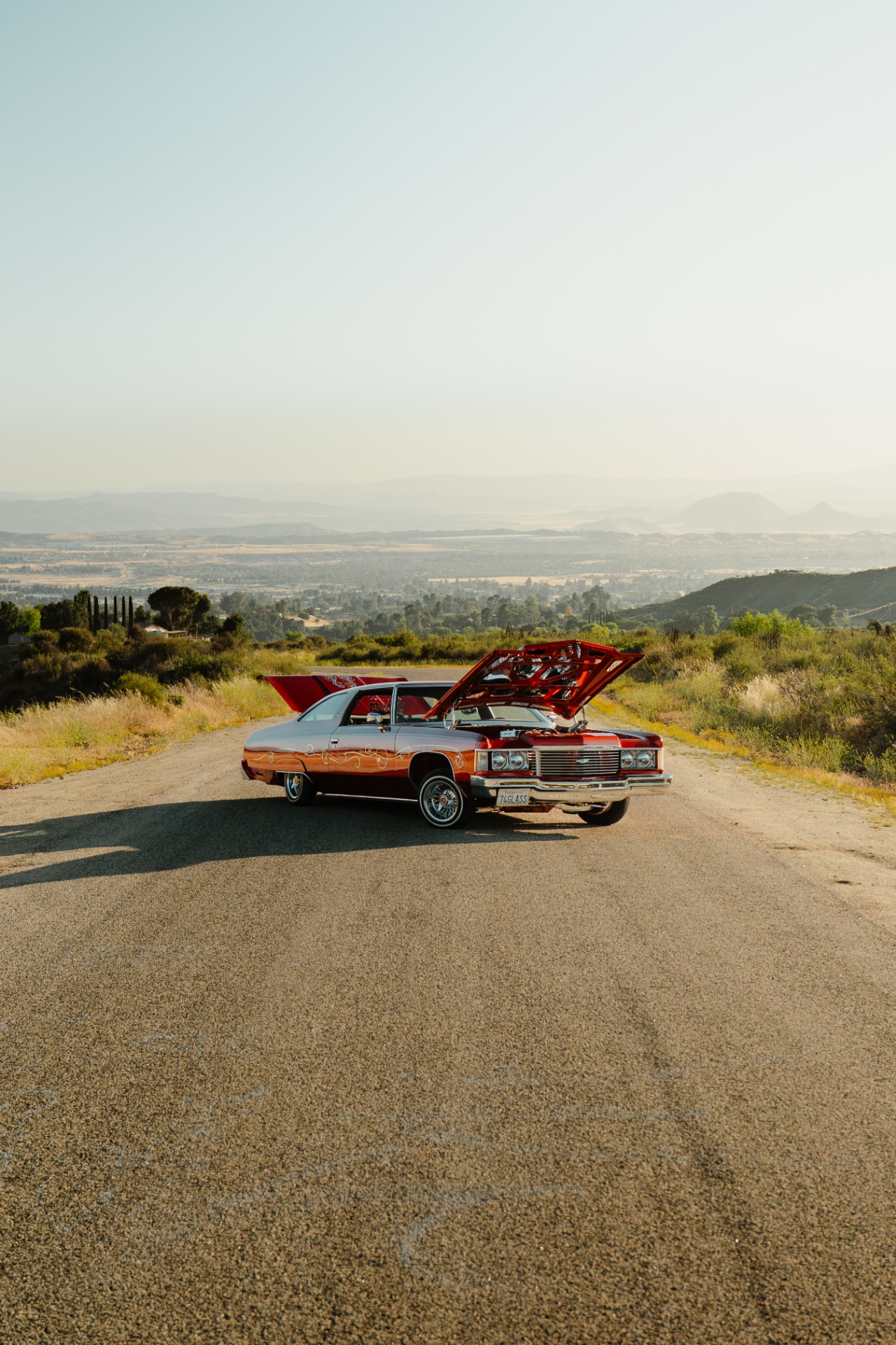 1974 Chevy with hood and trunk open, mountain vista behind