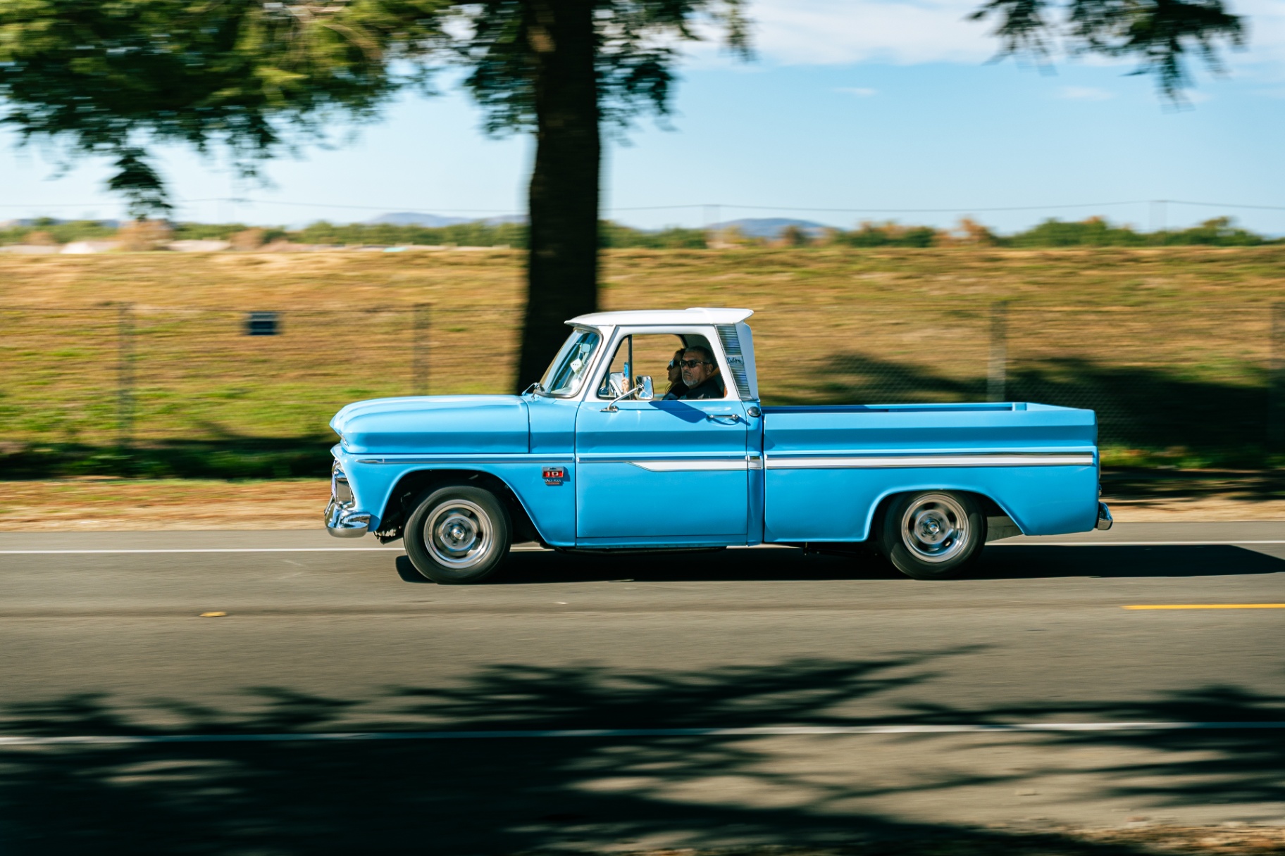 Baby blue classic Chevy C10 pickup cruising past golden hillsides