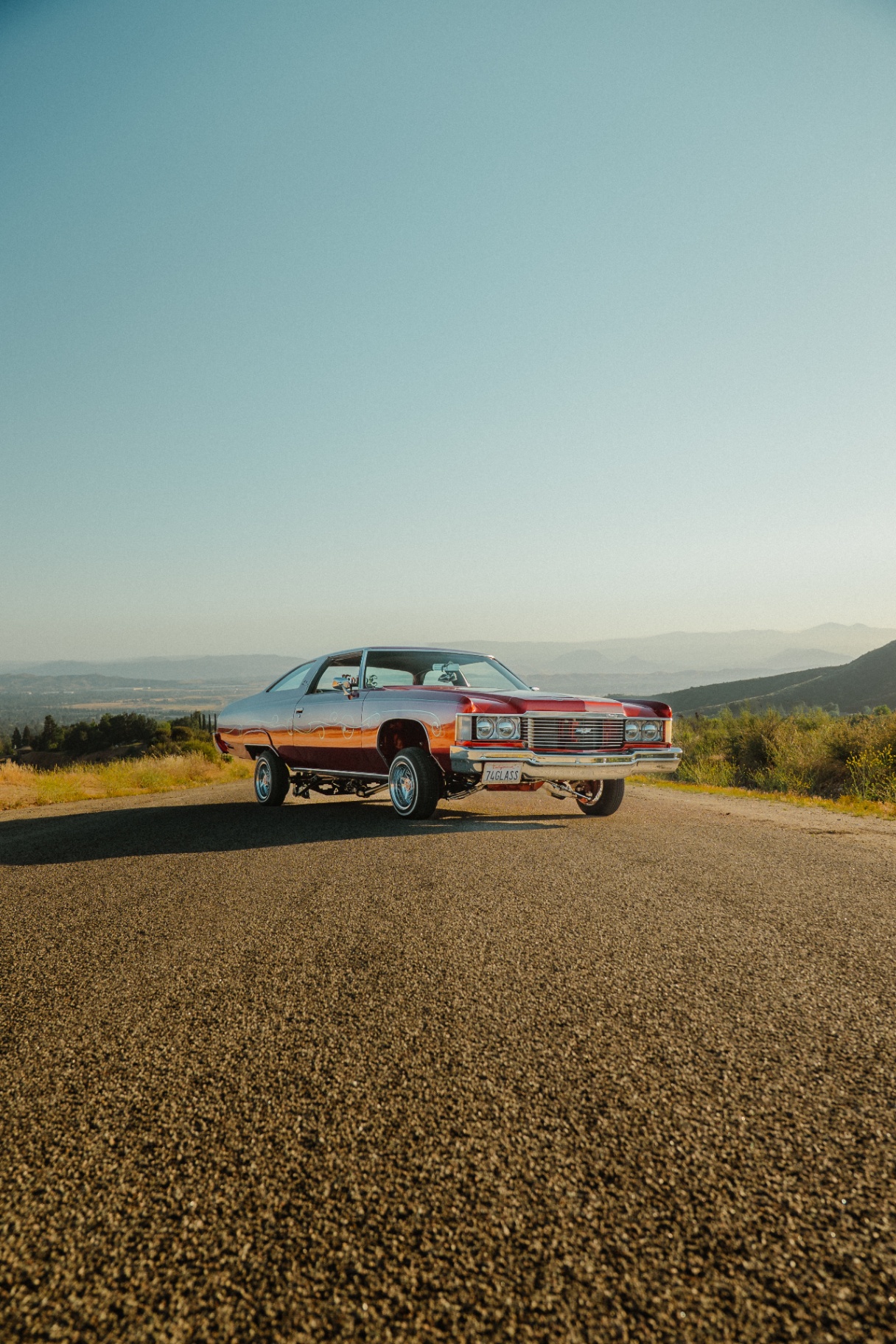 Custom candy-red 1974 Chevy on a hilltop overlooking the valley