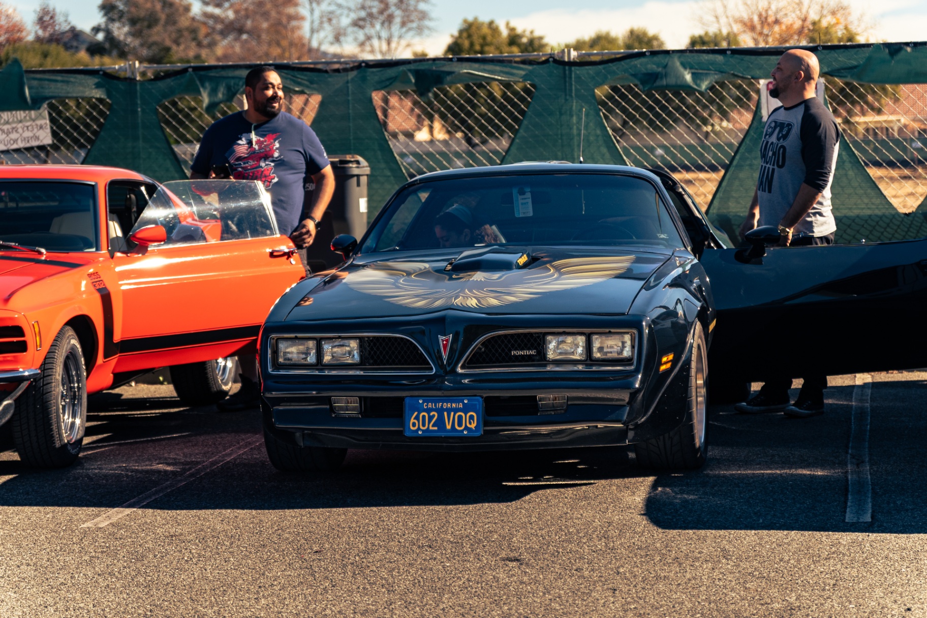 Black Pontiac Firebird Trans Am with gold screaming chicken hood, next to a red Boss 302