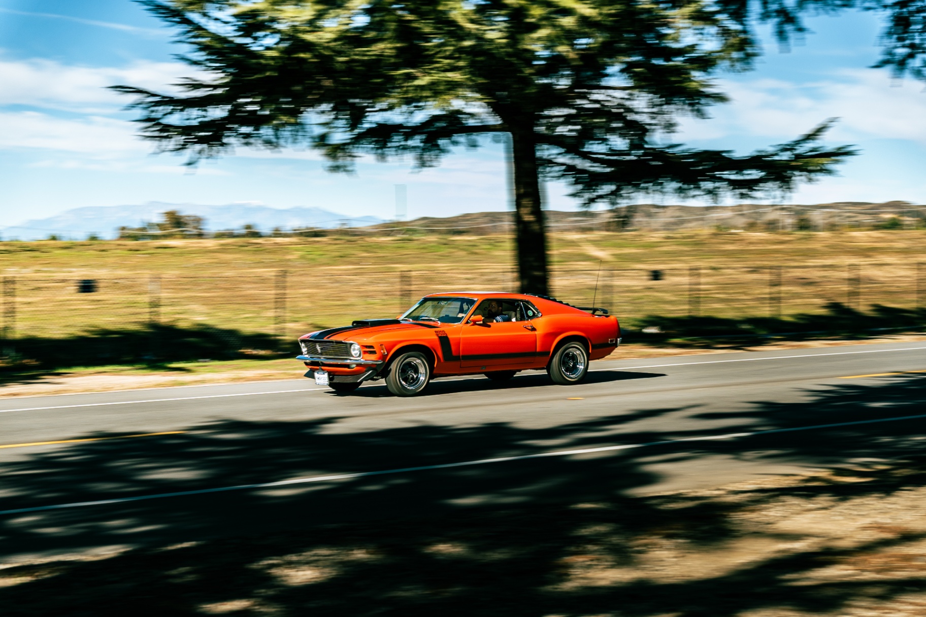 Orange Ford Mustang Boss 302 panning down the open road