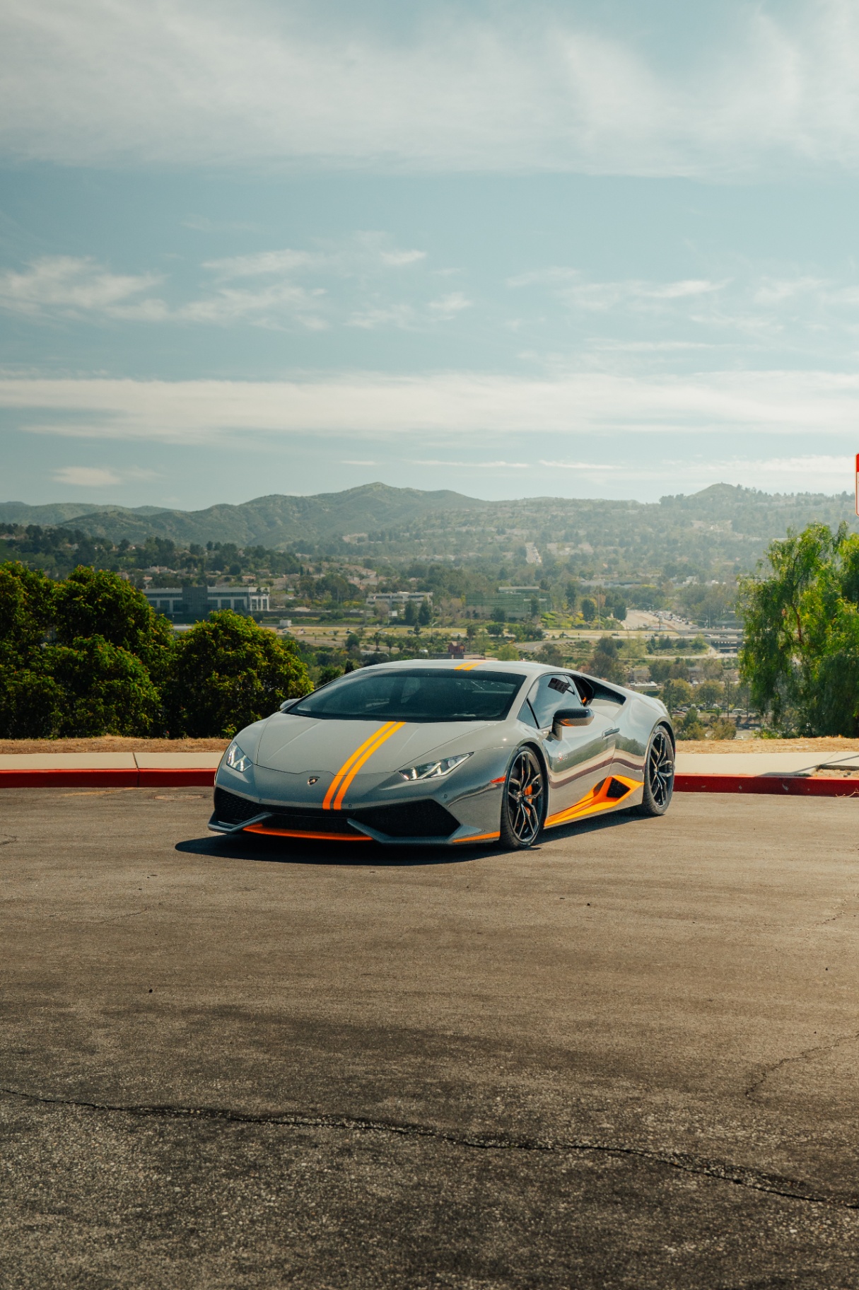 Grigio Lamborghini Huracán with orange racing stripes overlooking the valley